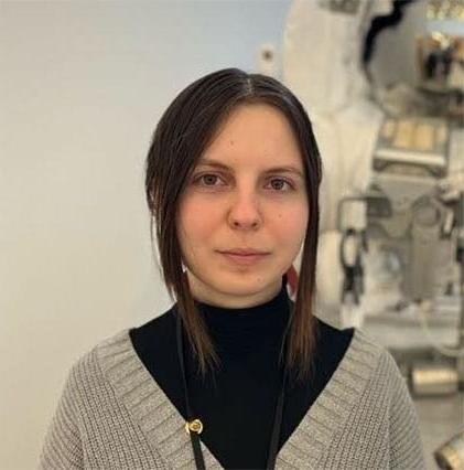 Eva T. from Ohio Connections Academy in a black shirt and brown sweater standing in front of a space suit display. 