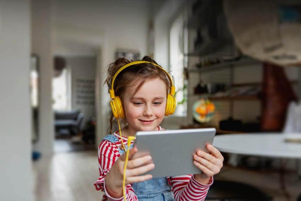 Young student in a red striped shirt and yellow headphones taking an online class at Michigan's Lighthouse Connections Academy.